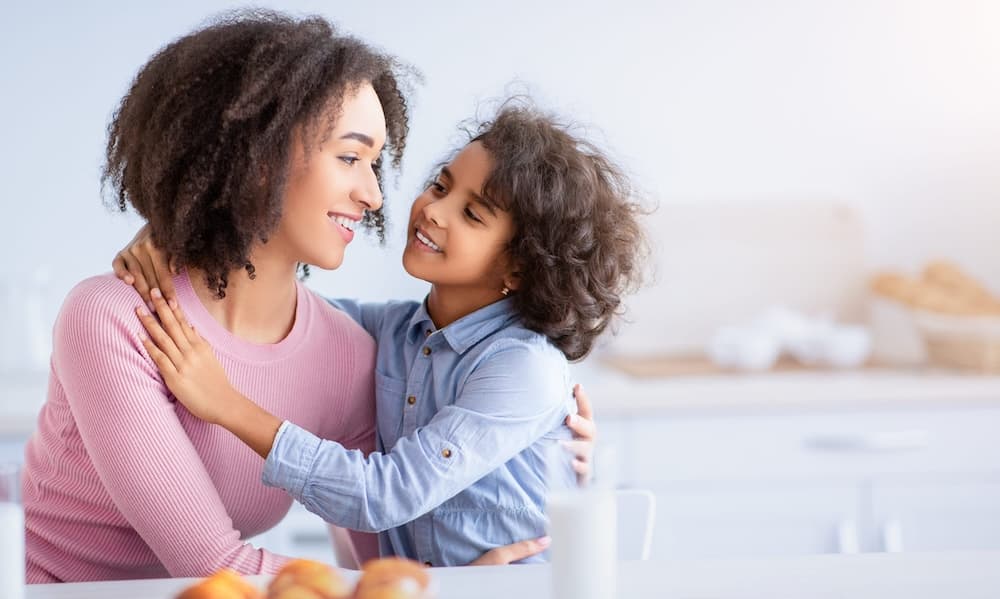 Parent gently checking a smiling child's hair for head lice